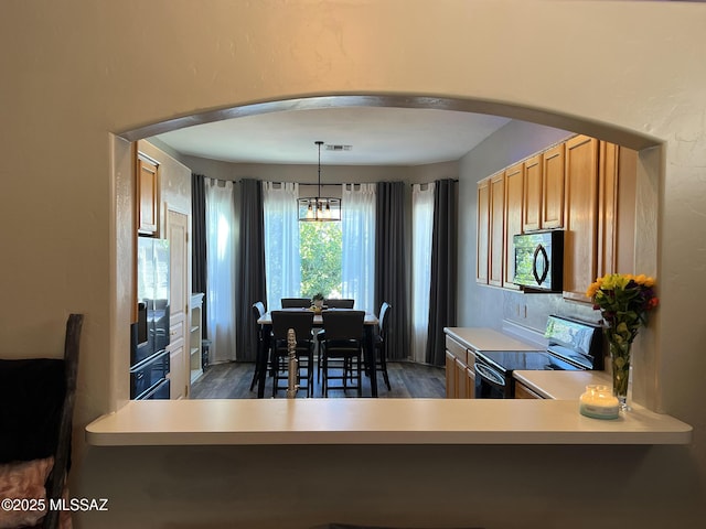 kitchen featuring an inviting chandelier, electric range oven, decorative light fixtures, and dark wood-type flooring