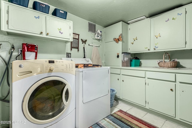 washroom with cabinets, light tile patterned floors, and washing machine and clothes dryer