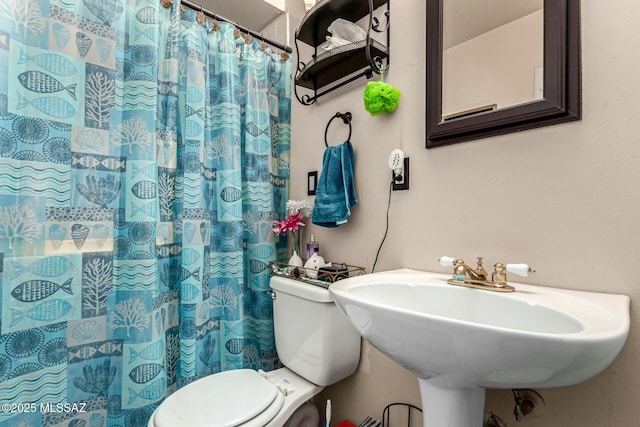 bathroom featuring a shower with shower curtain, toilet, and sink