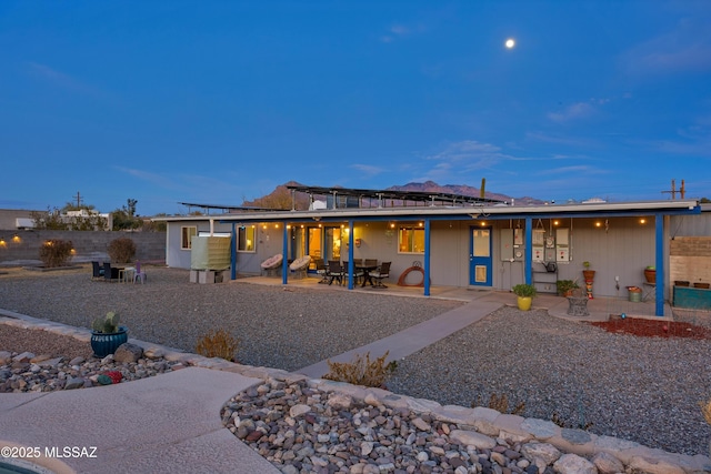 back house at dusk featuring a patio