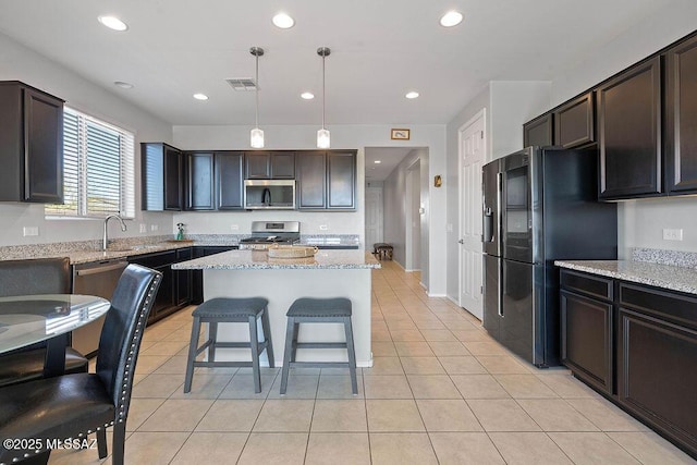 kitchen featuring pendant lighting, dark brown cabinets, appliances with stainless steel finishes, and a kitchen island