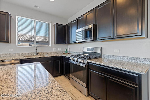 kitchen featuring stainless steel appliances, light stone countertops, sink, and light tile patterned floors