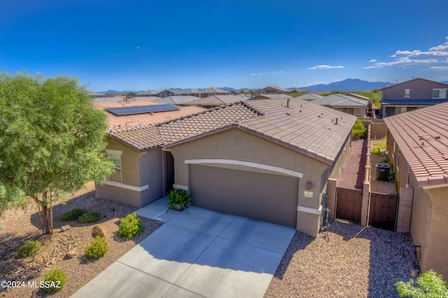 view of front of house with a garage, a mountain view, central AC, and solar panels