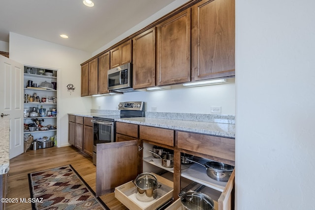 kitchen featuring light stone counters, appliances with stainless steel finishes, and light hardwood / wood-style flooring