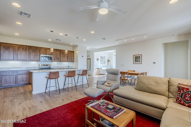 living room featuring ceiling fan, sink, and light hardwood / wood-style floors