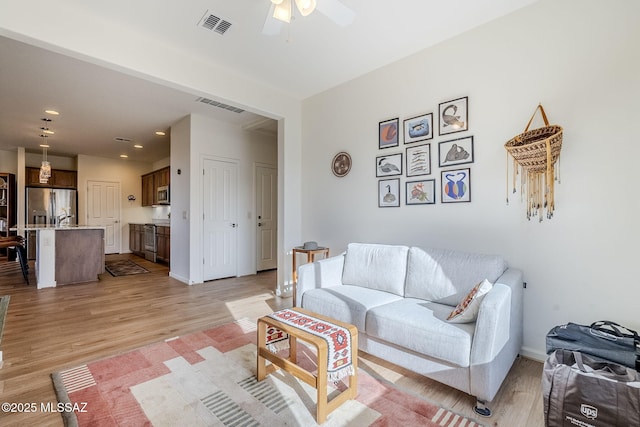 living room featuring ceiling fan and light hardwood / wood-style floors