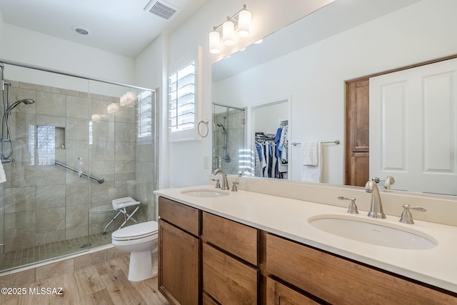 bathroom with vanity, hardwood / wood-style floors, a shower with door, and toilet