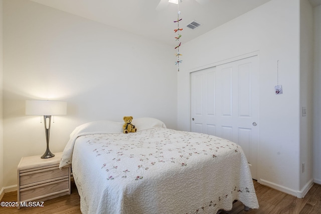 bedroom featuring hardwood / wood-style flooring, ceiling fan, and a closet