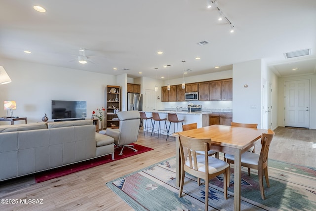 dining area featuring ceiling fan, sink, and light wood-type flooring