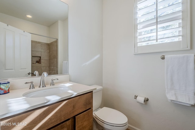 bathroom with vanity, a tile shower, and toilet