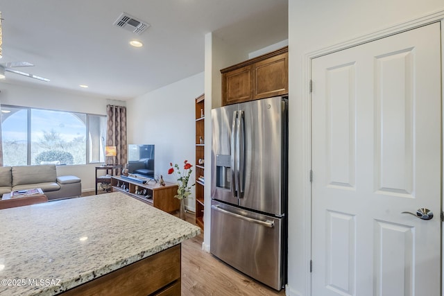 kitchen featuring stainless steel fridge, light stone countertops, and light hardwood / wood-style floors