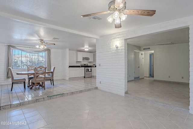 unfurnished dining area featuring visible vents, light tile patterned floors, and a ceiling fan