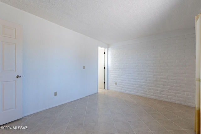 spare room featuring brick wall and a textured ceiling
