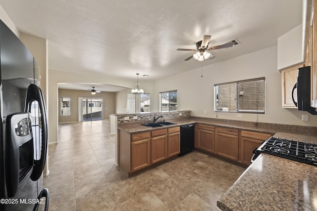 kitchen featuring a wealth of natural light, pendant lighting, kitchen peninsula, sink, and black appliances