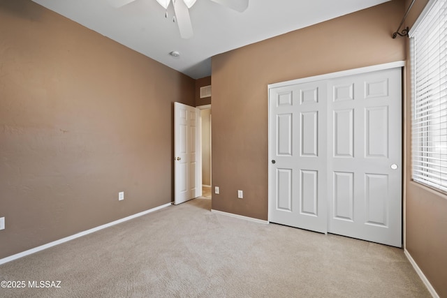 unfurnished bedroom featuring light carpet, a closet, and ceiling fan