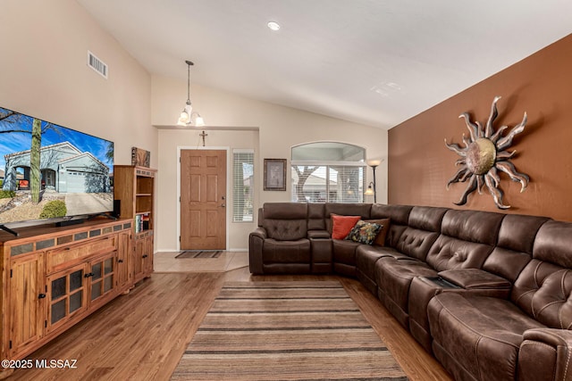 living area with visible vents, vaulted ceiling, and wood finished floors