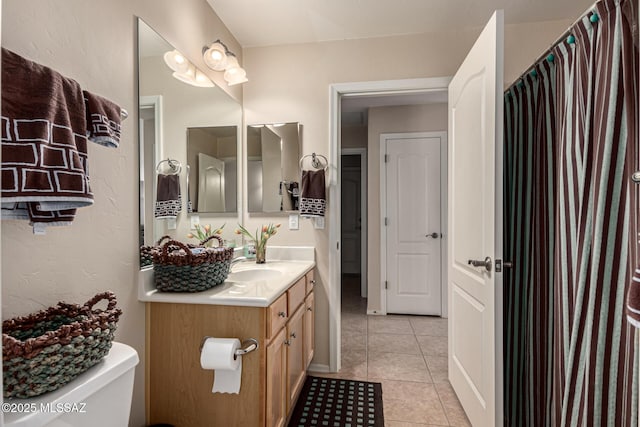 bathroom with toilet, vanity, and tile patterned flooring