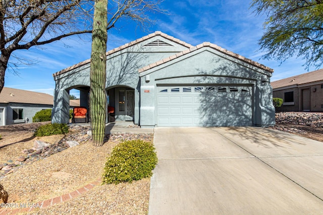 ranch-style house featuring a garage, concrete driveway, a tile roof, and stucco siding