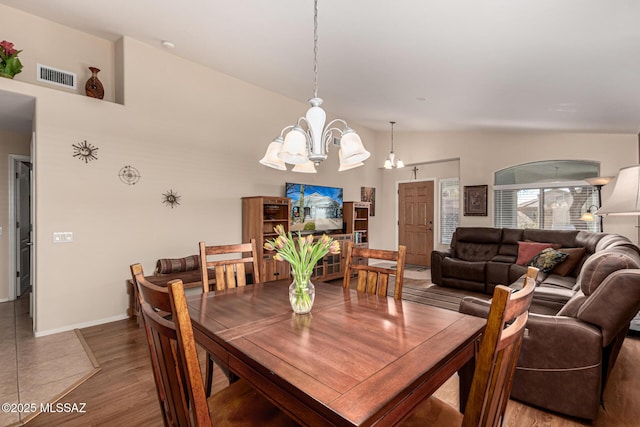 dining room featuring a notable chandelier, wood-type flooring, and lofted ceiling