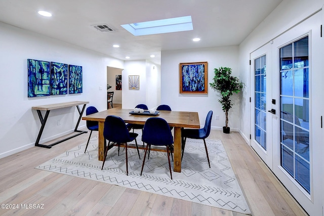 dining space featuring a skylight, french doors, and light wood-type flooring