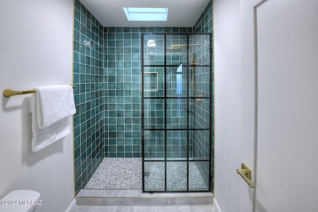 bathroom with a skylight, a tile shower, and toilet