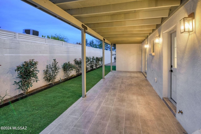 patio terrace at dusk featuring a yard