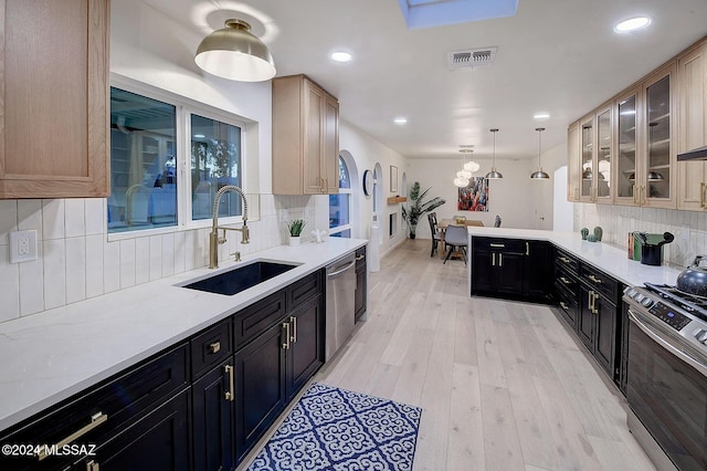 kitchen featuring light brown cabinetry, appliances with stainless steel finishes, decorative backsplash, sink, and decorative light fixtures