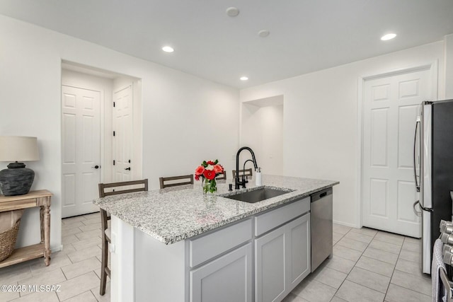 kitchen featuring sink, a kitchen bar, appliances with stainless steel finishes, and a center island with sink