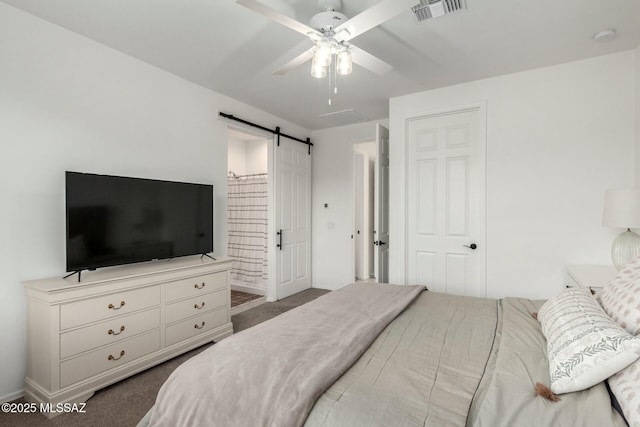 carpeted bedroom with a barn door and ceiling fan