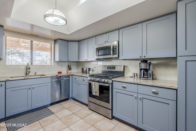 kitchen with sink, decorative backsplash, light stone countertops, and appliances with stainless steel finishes