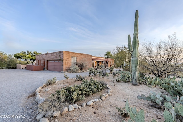 pueblo-style house with aphalt driveway and an attached garage