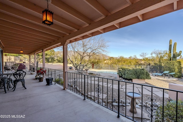 view of patio with a fenced in pool and a balcony