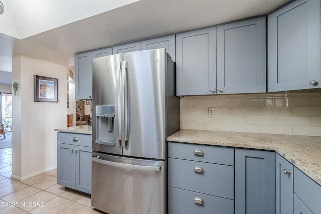 kitchen featuring light tile patterned floors, light stone countertops, stainless steel fridge with ice dispenser, and backsplash