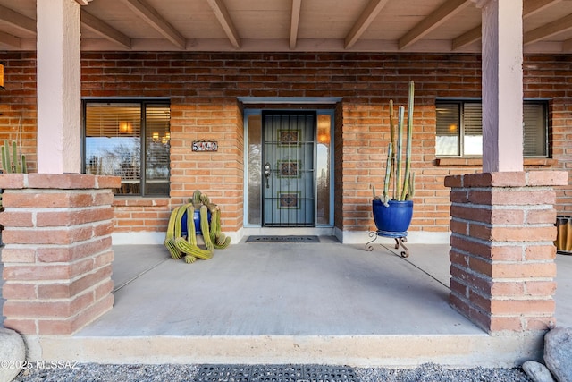 entrance to property featuring covered porch and brick siding