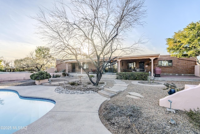 back of property featuring a patio area, a fenced in pool, brick siding, and fence