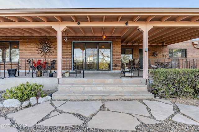 view of exterior entry with brick siding and a porch