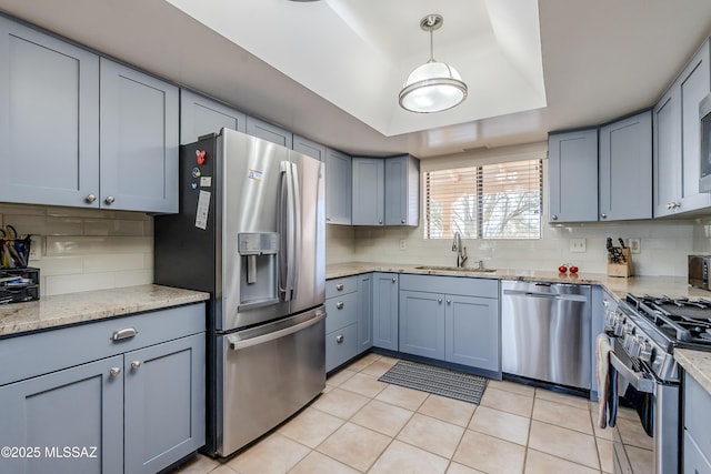 kitchen featuring decorative backsplash, appliances with stainless steel finishes, a tray ceiling, and a sink