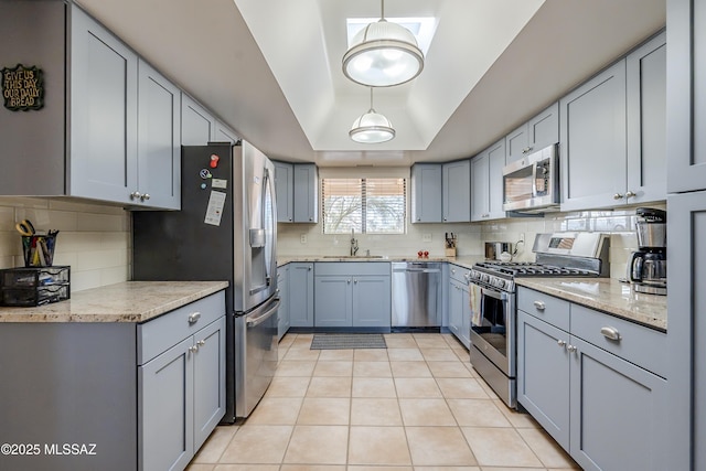 kitchen featuring decorative backsplash, light tile patterned flooring, stainless steel appliances, a raised ceiling, and a sink