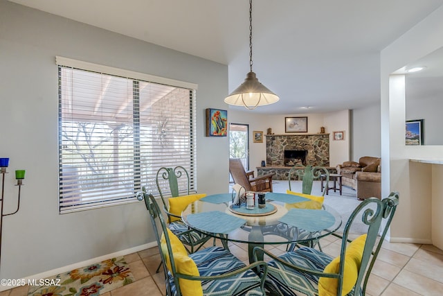 dining area featuring light tile patterned flooring, a fireplace, and baseboards