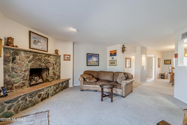 living area with visible vents, light colored carpet, and a stone fireplace