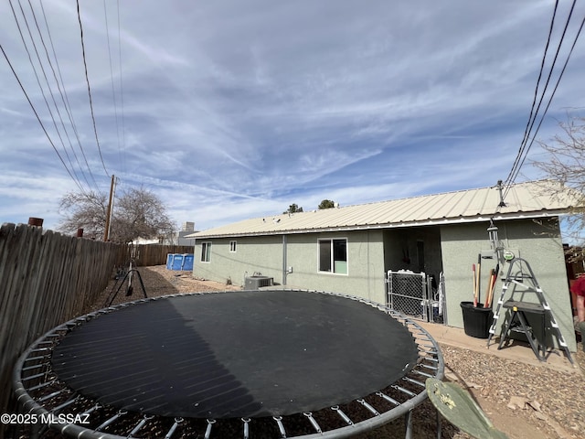 back of house featuring a trampoline and central AC