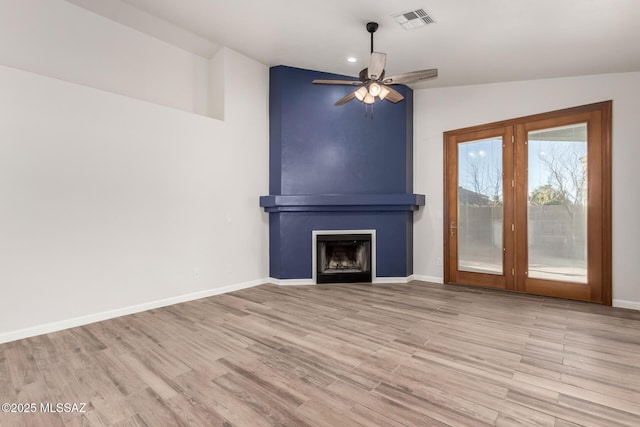 unfurnished living room with light hardwood / wood-style floors, a large fireplace, ceiling fan, and vaulted ceiling