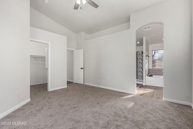 unfurnished bedroom featuring light carpet, ceiling fan, a spacious closet, a closet, and lofted ceiling