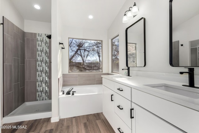 bathroom with hardwood / wood-style floors, independent shower and bath, and vanity