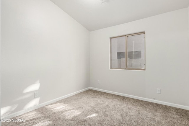 spare room featuring carpet and lofted ceiling