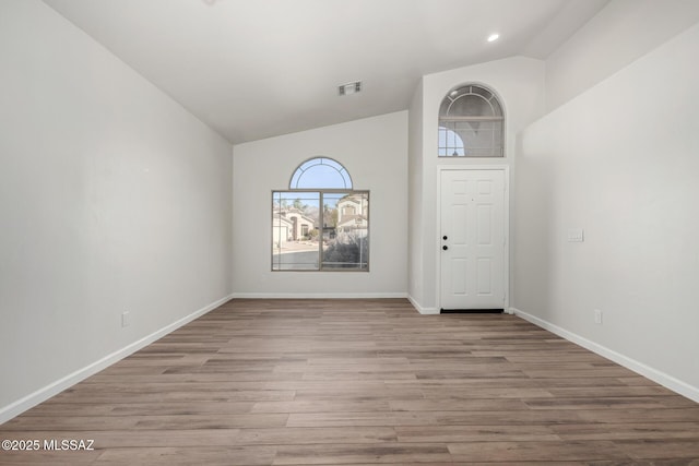 foyer with light wood-type flooring and high vaulted ceiling