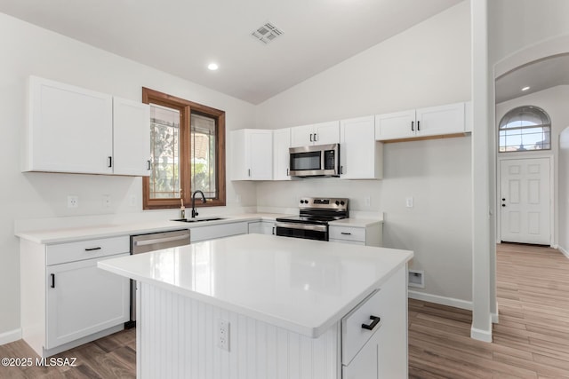 kitchen featuring sink, white cabinets, a kitchen island, lofted ceiling, and stainless steel appliances