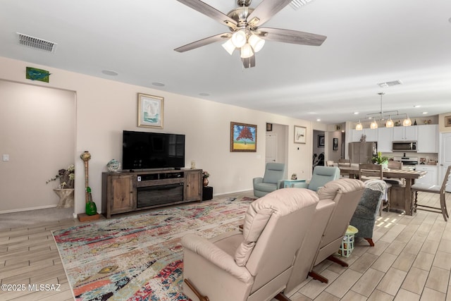 living area with light wood finished floors, visible vents, and baseboards