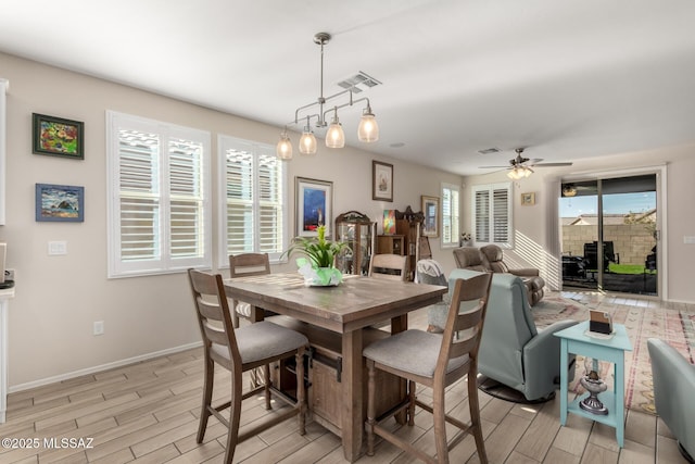 dining area with wood tiled floor, a ceiling fan, visible vents, and baseboards