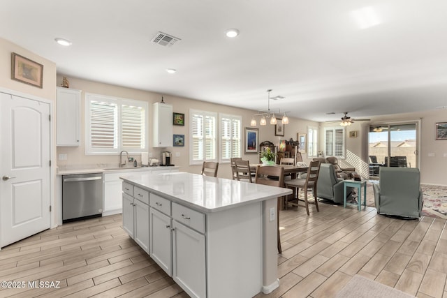 kitchen featuring white cabinetry, pendant lighting, a center island, and dishwasher